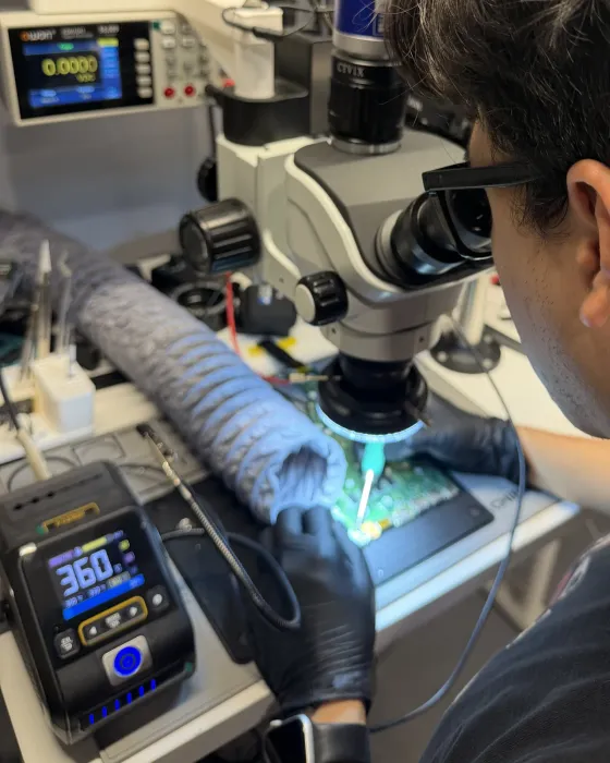Técnico de BestFixing reparando una placa base bajo el microscopio, con el soldador a 360 °C