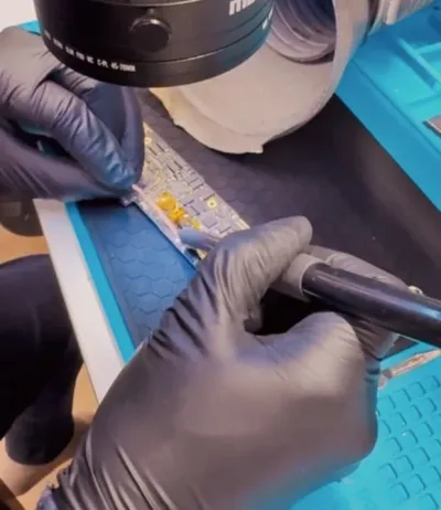 Reparación de una placa con microsoldadura bajo lámpara de aumento, con guantes de nitrilo