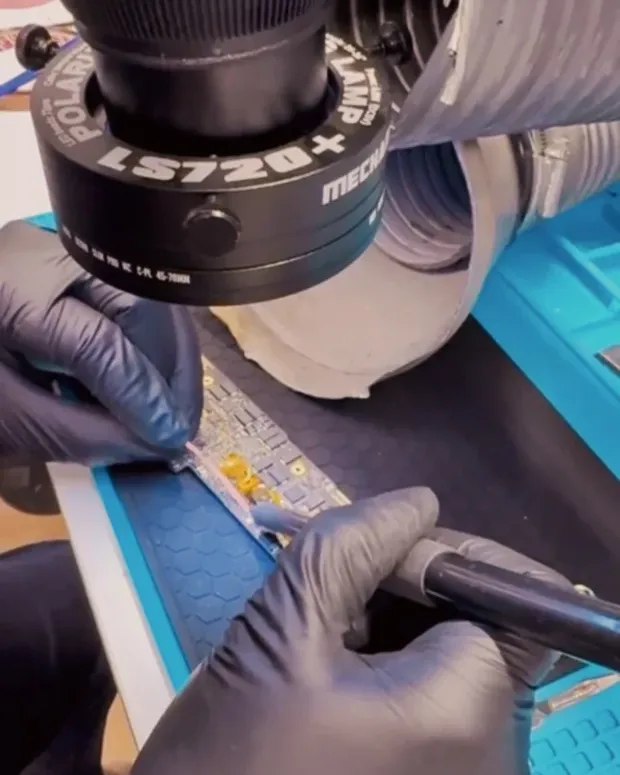 Reparación de una placa con microsoldadura bajo lámpara de aumento, con guantes de nitrilo