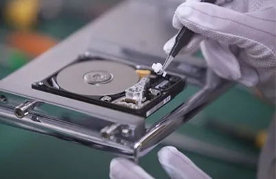 Técnico con guantes abriendo un disco duro con pinzas para recuperar los datos