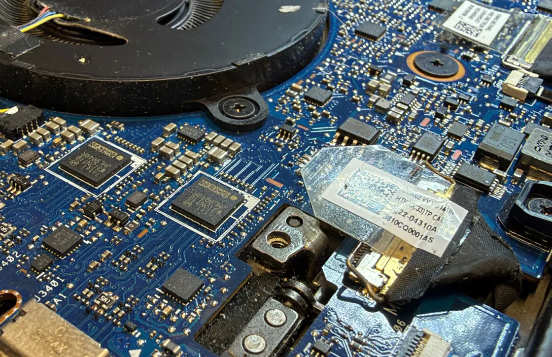 Detalle de una placa de portátil con sus circuitos integrados, conectores y bisagra