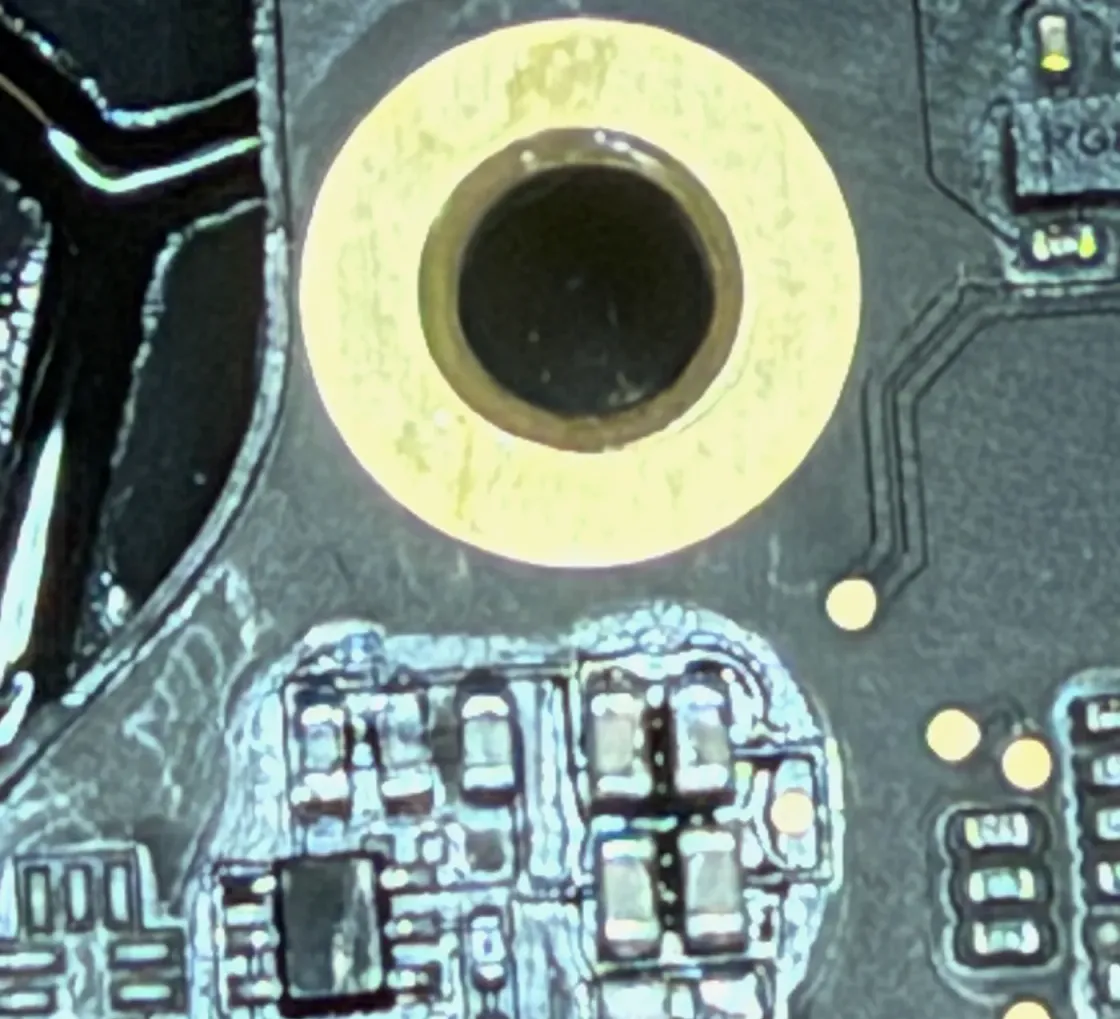 Microscope view of a board area with white corrosion around the components, typical of liquid damage